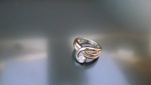 A continous ribbon of precious metal swirls up and around your finger to hold a 1/5 carat stunning diamond